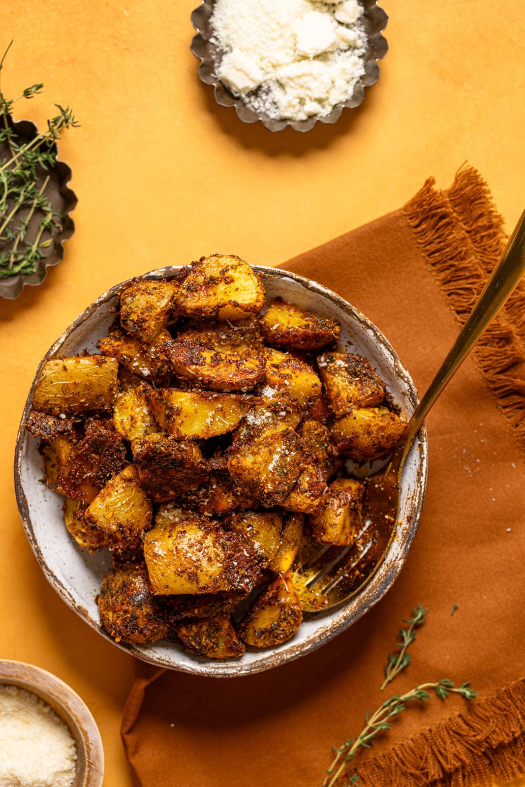 Roasted potatoes in a dish with a spoon and brown napkin.
