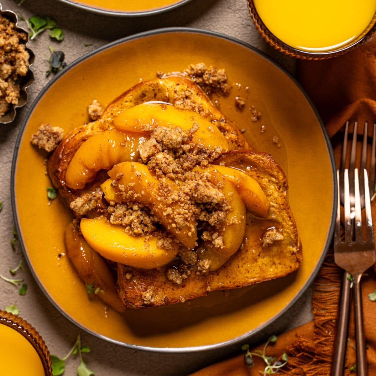 Up close shot of french toast in a yellow plate with forks and orange juice.