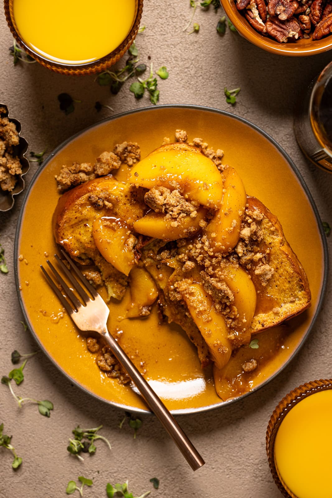 Eaten french toast on a yellow plate with a fork and orange juice and pecans.