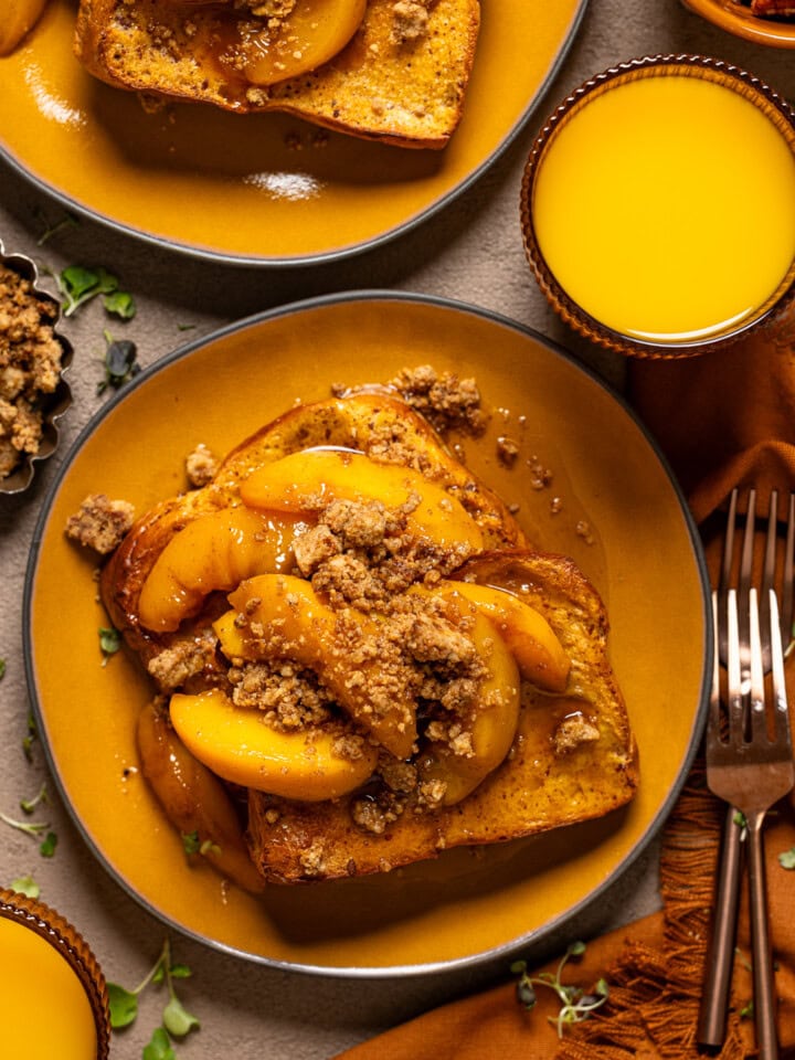 Up close shot of french toast in a yellow plate with forks and orange juice.