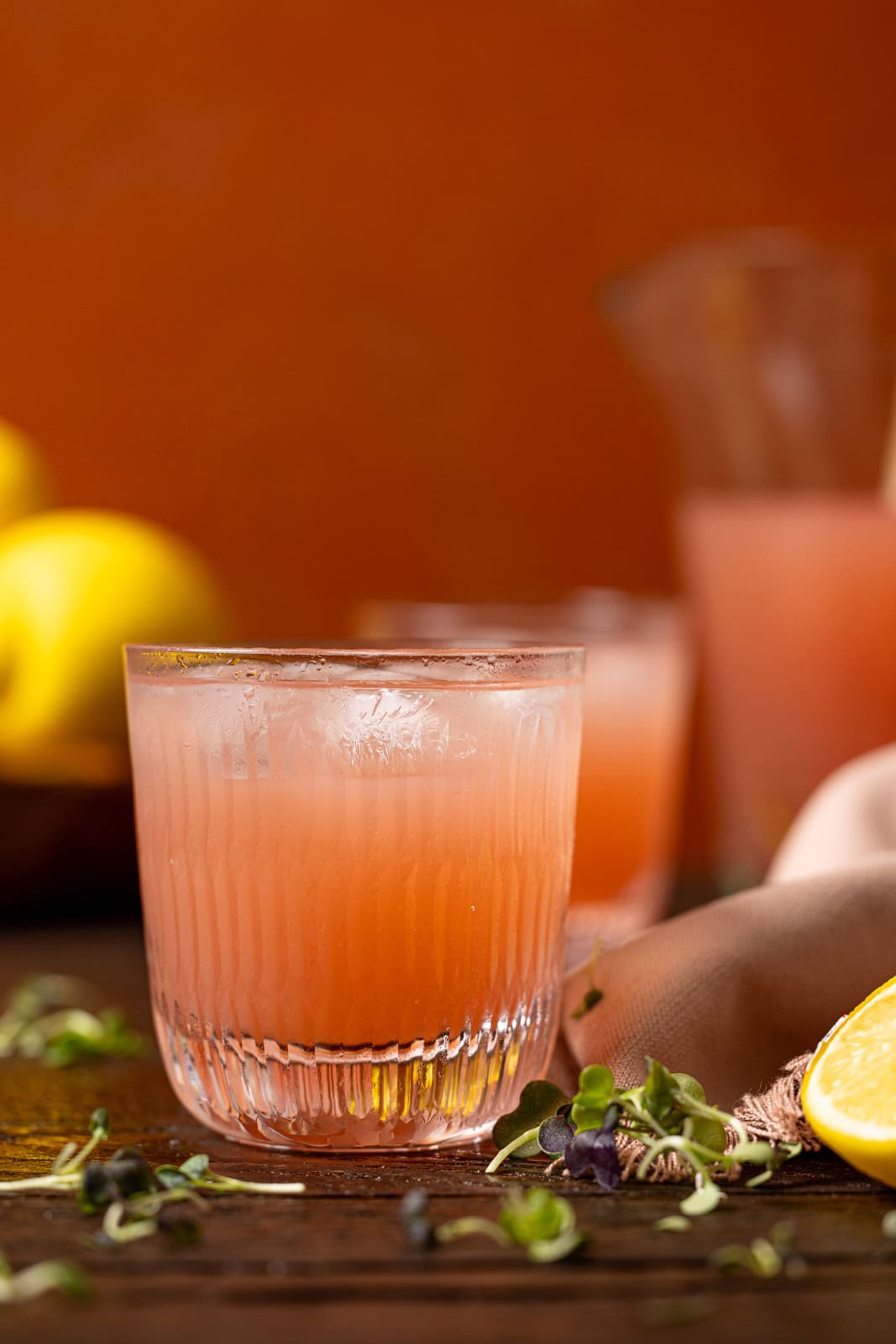 Two glasses of lemonade on a brown wood table.