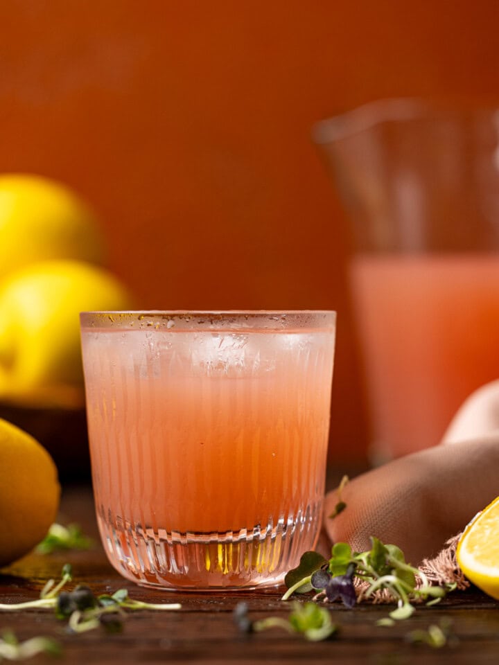 Up close shot of pink lemonade in a glass with lemons.