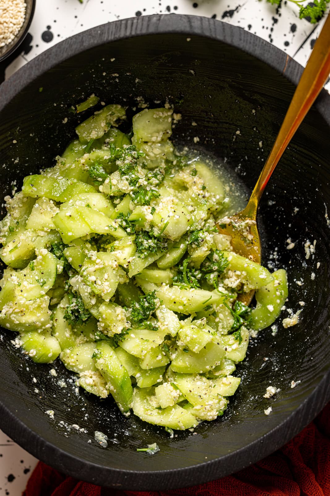 Up close shot of cucumber salad in a black bowl with a spoon.