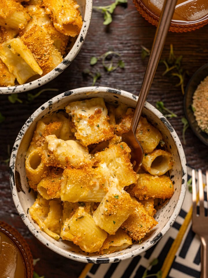 Bowl of mac and cheese on a wood table with forks.