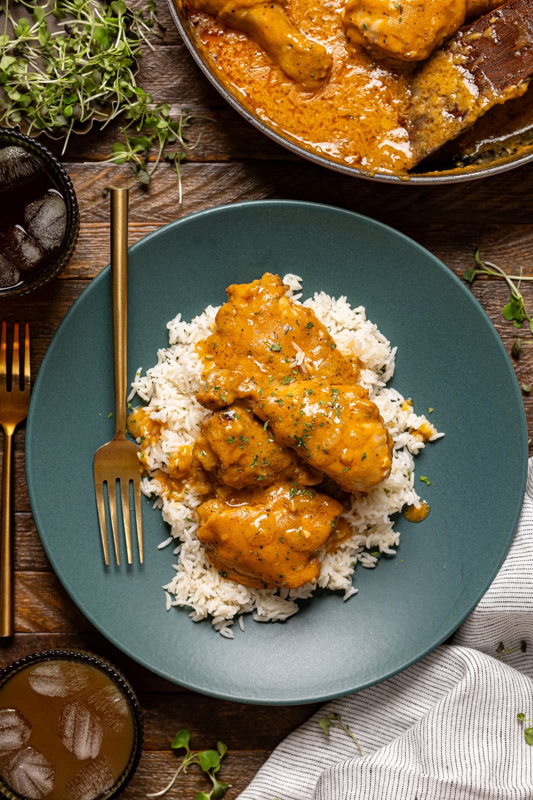 Chicken on a green plate with a fork, side of drink, and a pot.