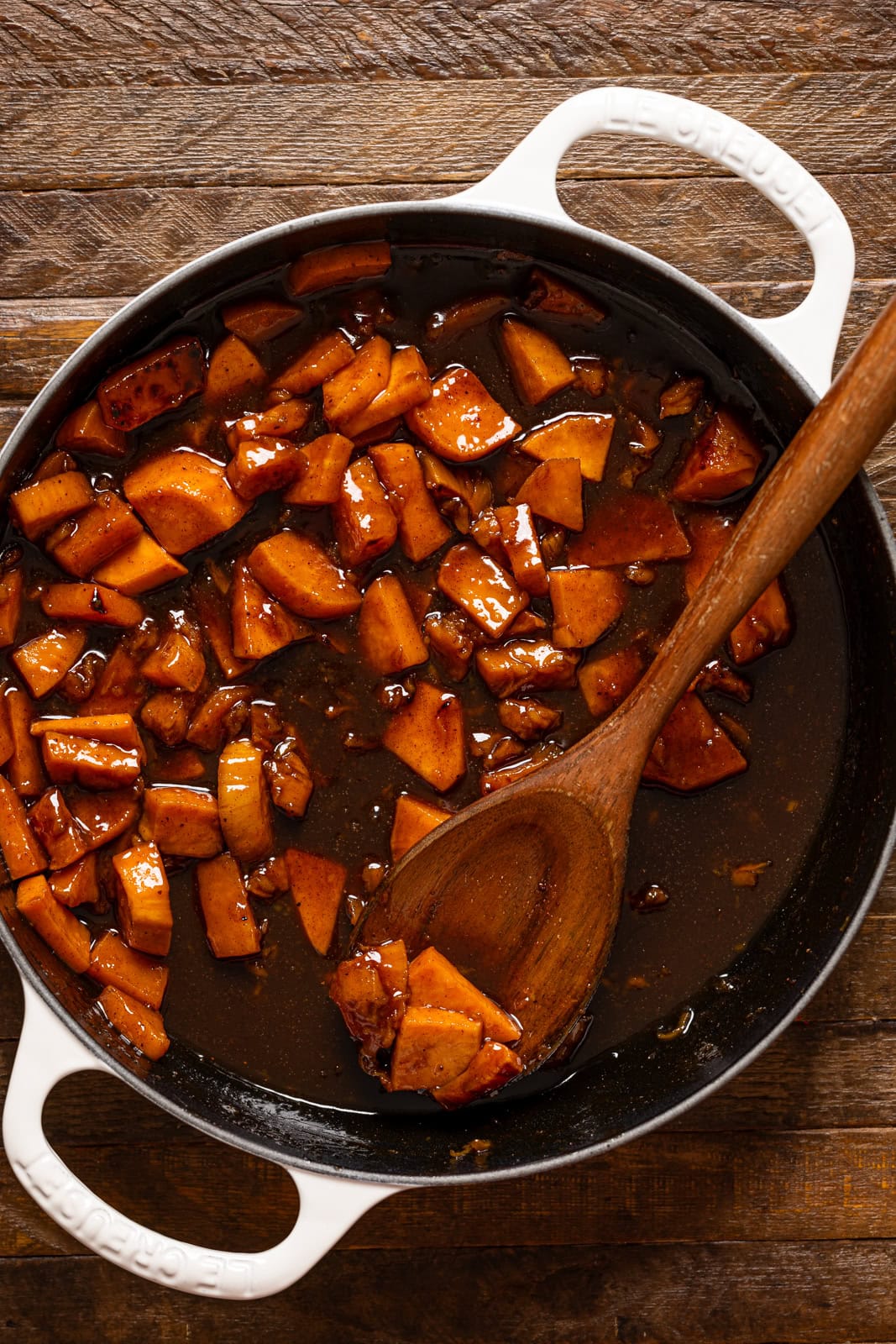 Yams in a white pot with a wooden spoon.