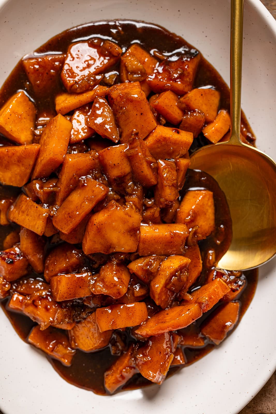 Up close shot of sweet potatoes on a platter with a spoon.