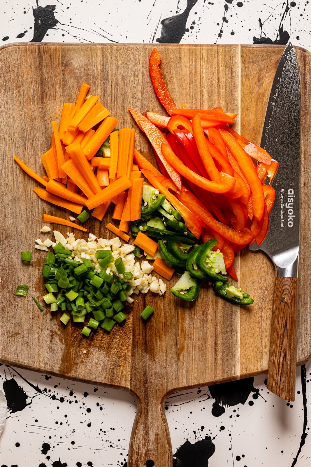 Chopped veggies on a cutting board with a knife.