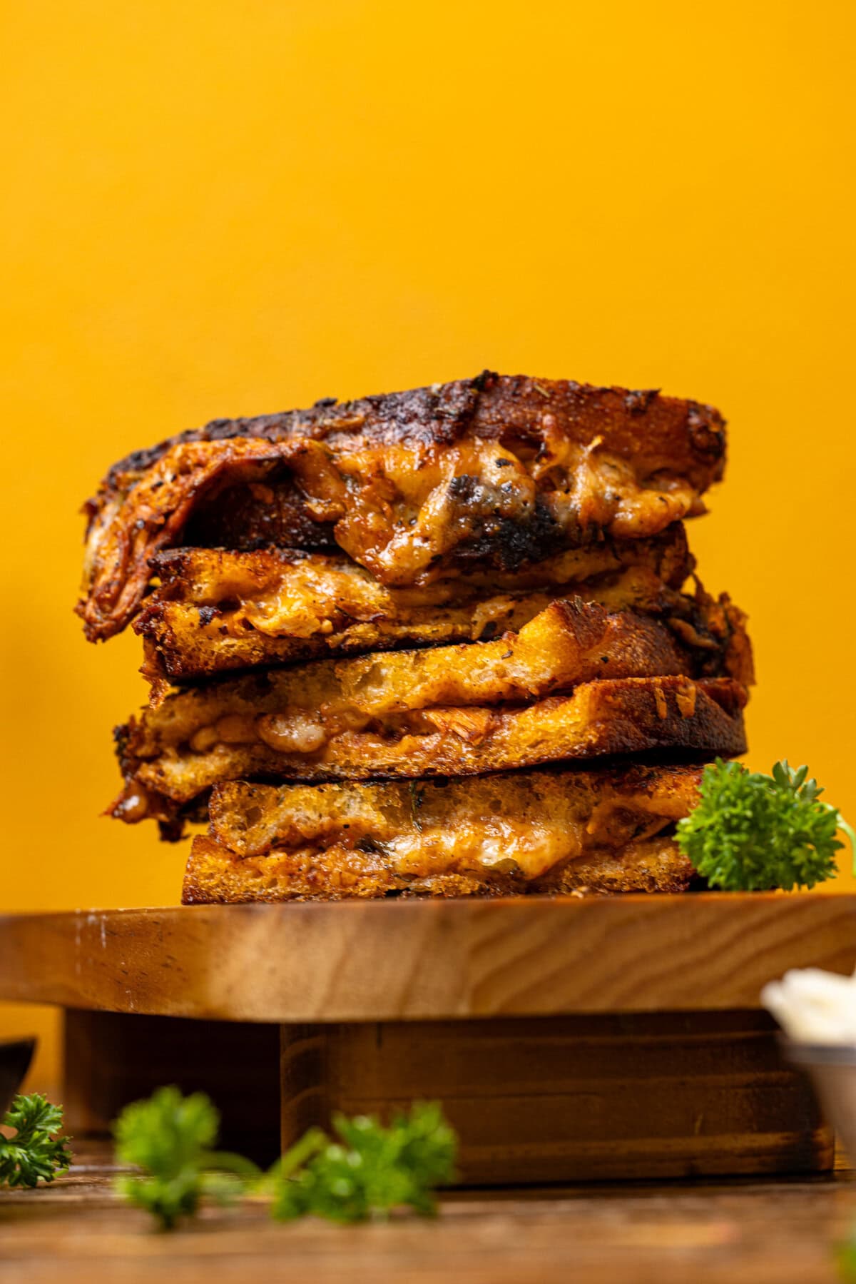 Stack of grilled cheese with a yellow background.