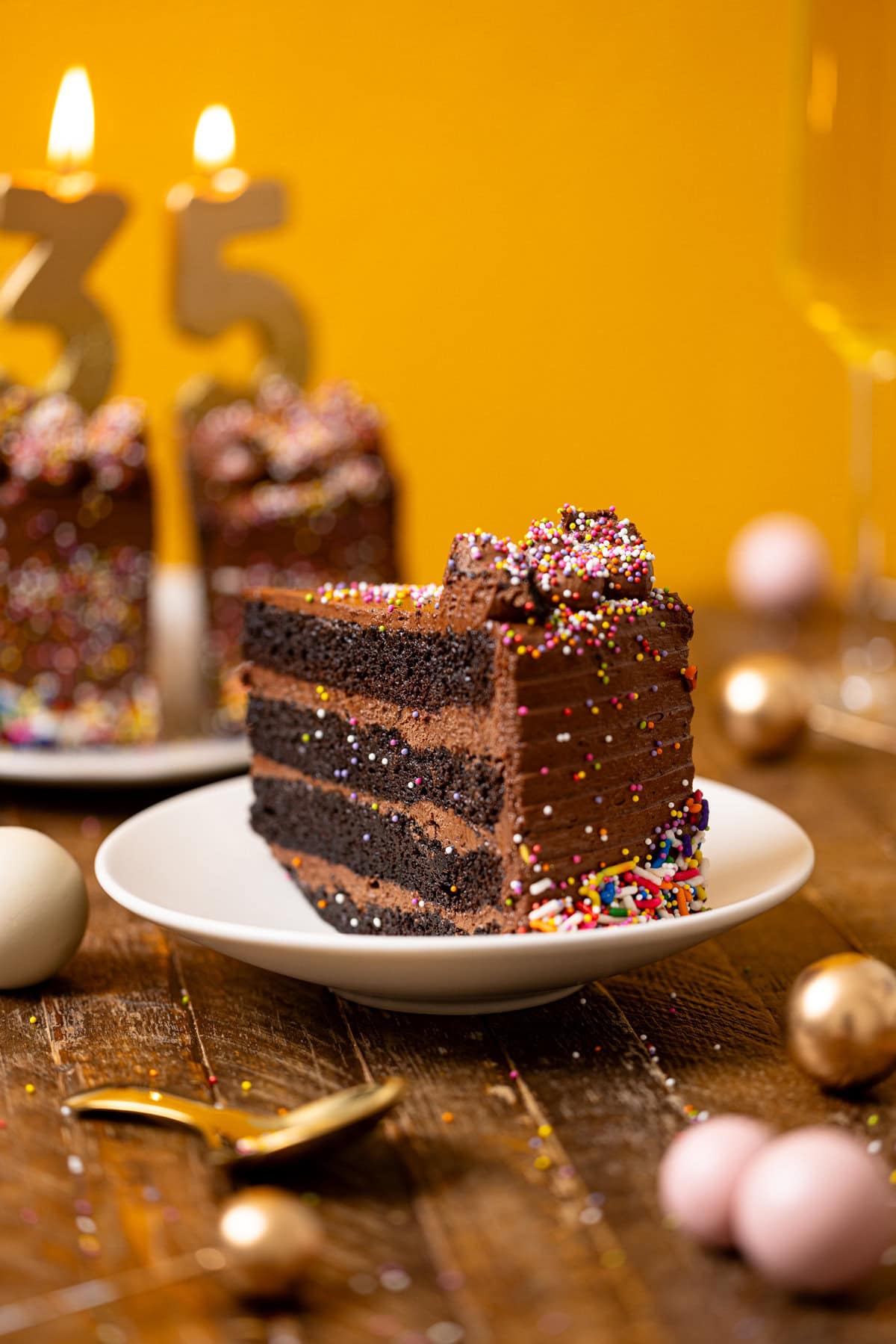 Slice of chocolate cake on a white plate with slices in background, a spoon, and balloon.