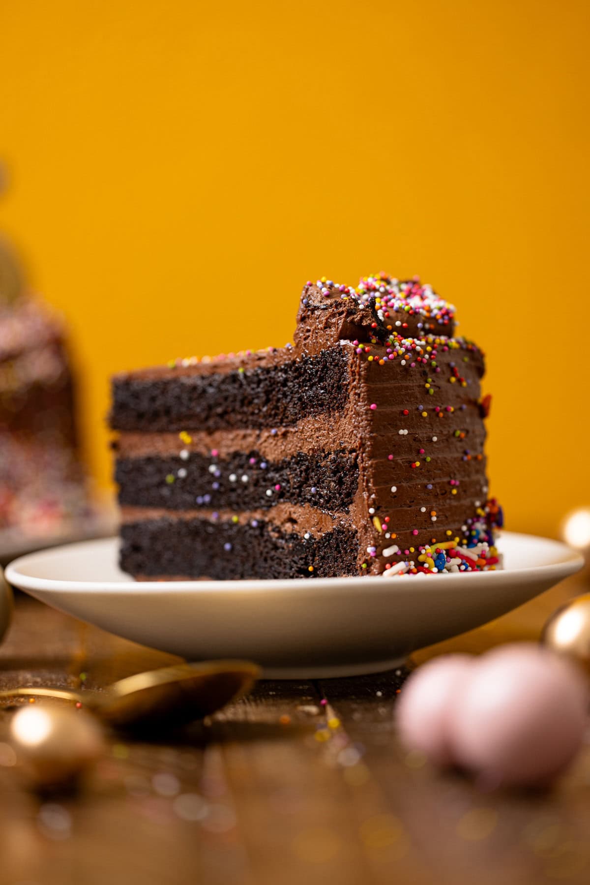 Forward shot of chocolate cake on a white plate with a yellow background.