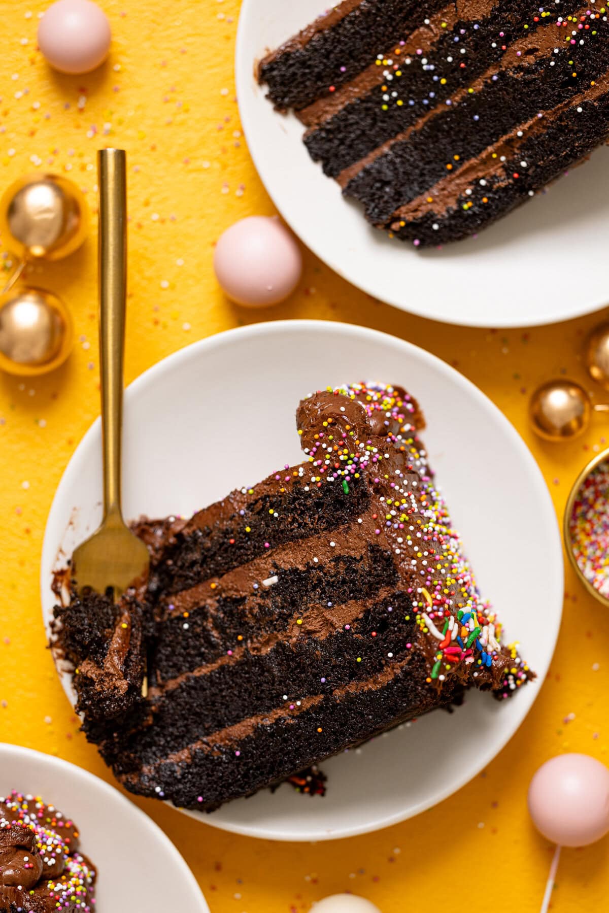 Shot of chocolate cake slice on a white plate with a fork and balloons.