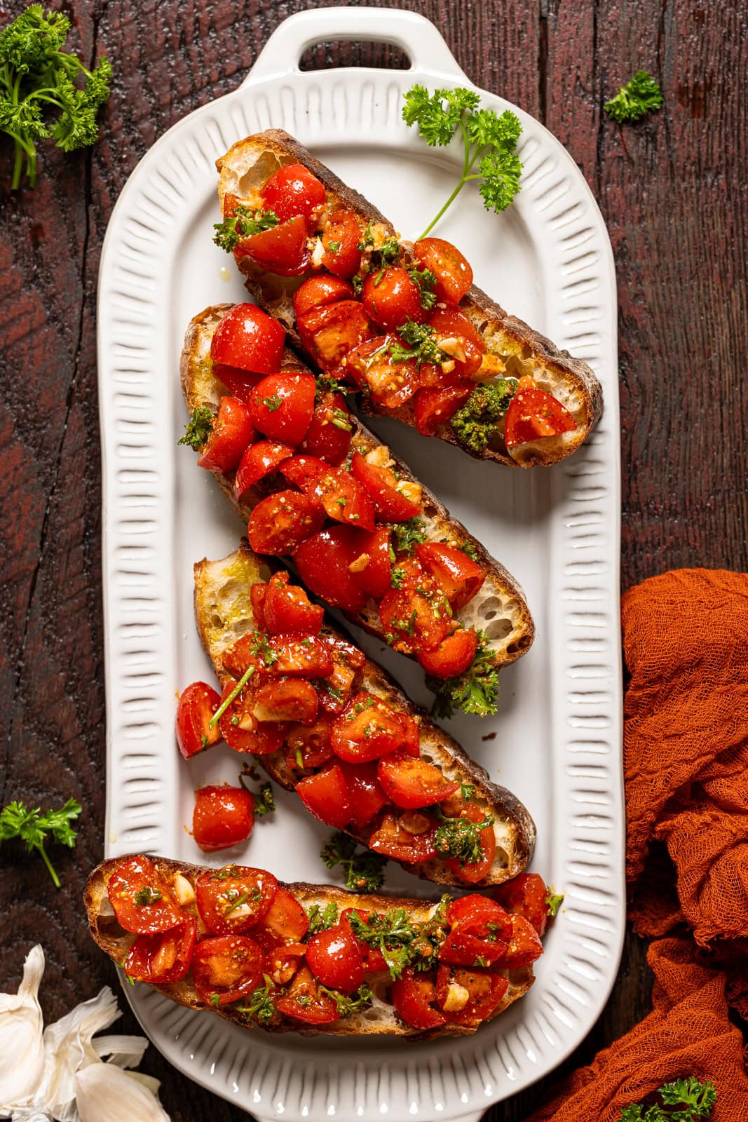 Bruschetta on a platter with herb garnish and a red napkin.