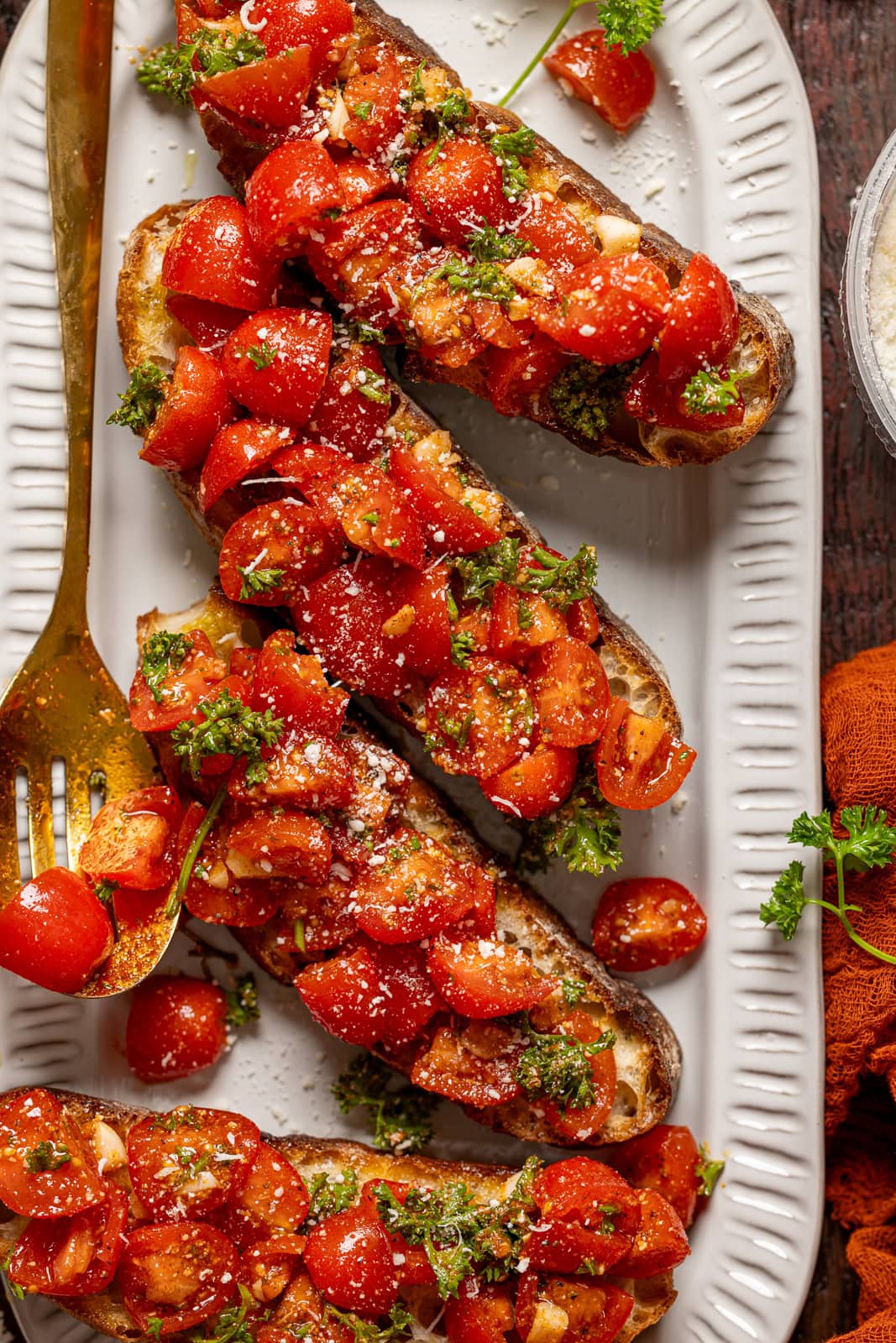 Bruschettas on a platter with a gold spoon.