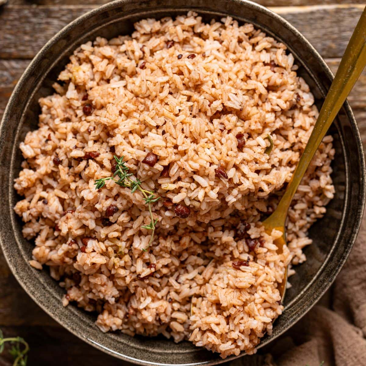 Rice and peas in a bowl with a gold spoon.
