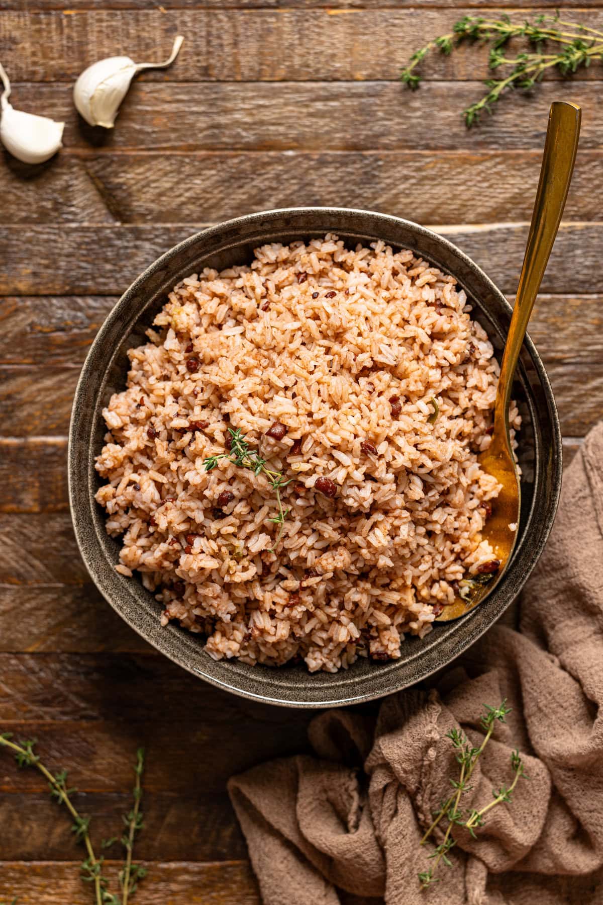 Rice and peas in a serving bowl with a spoon on a brown wood table.