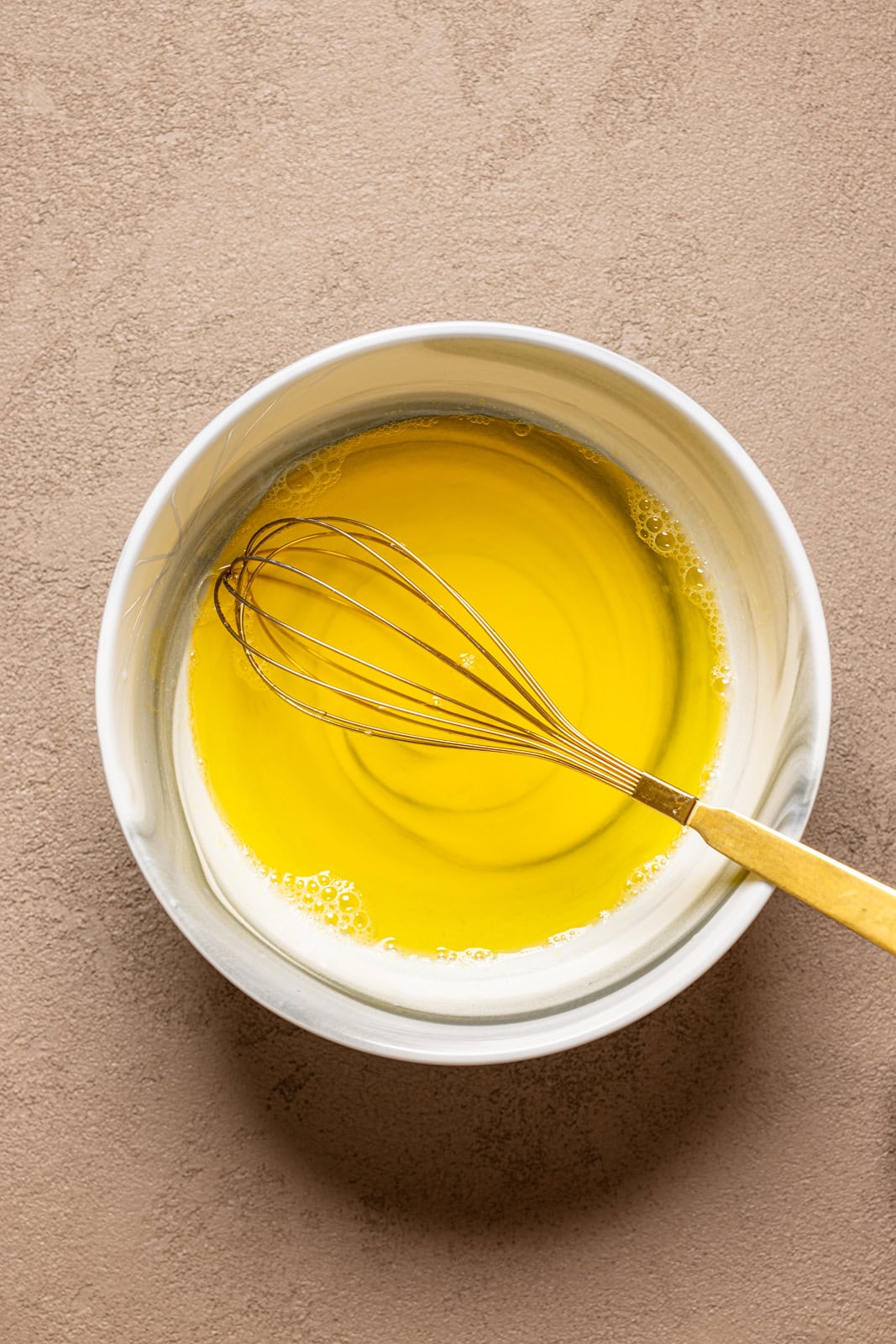 Jello mixture in a marble bowl with a whisk.