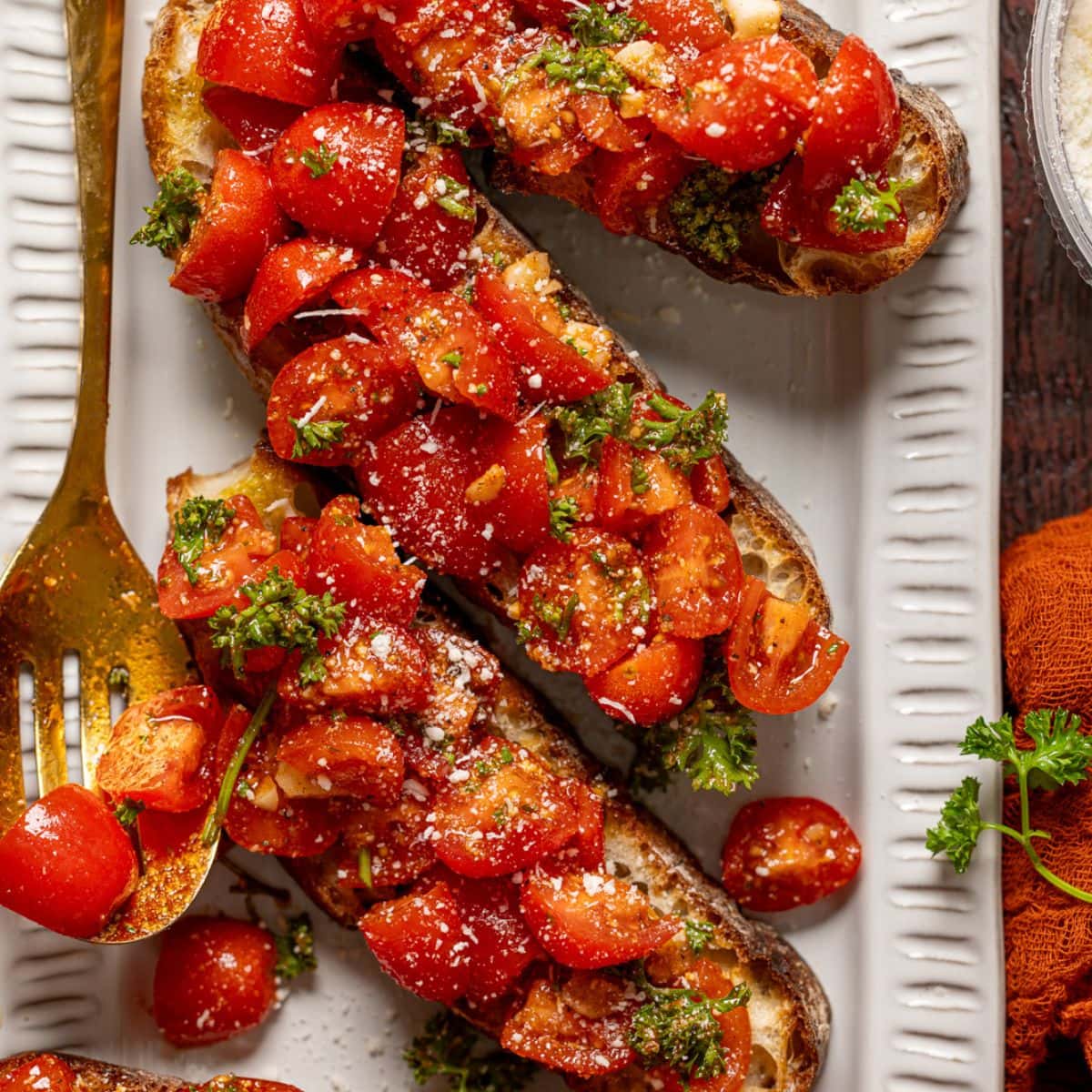 Bruschettas on a platter with a gold spoon.