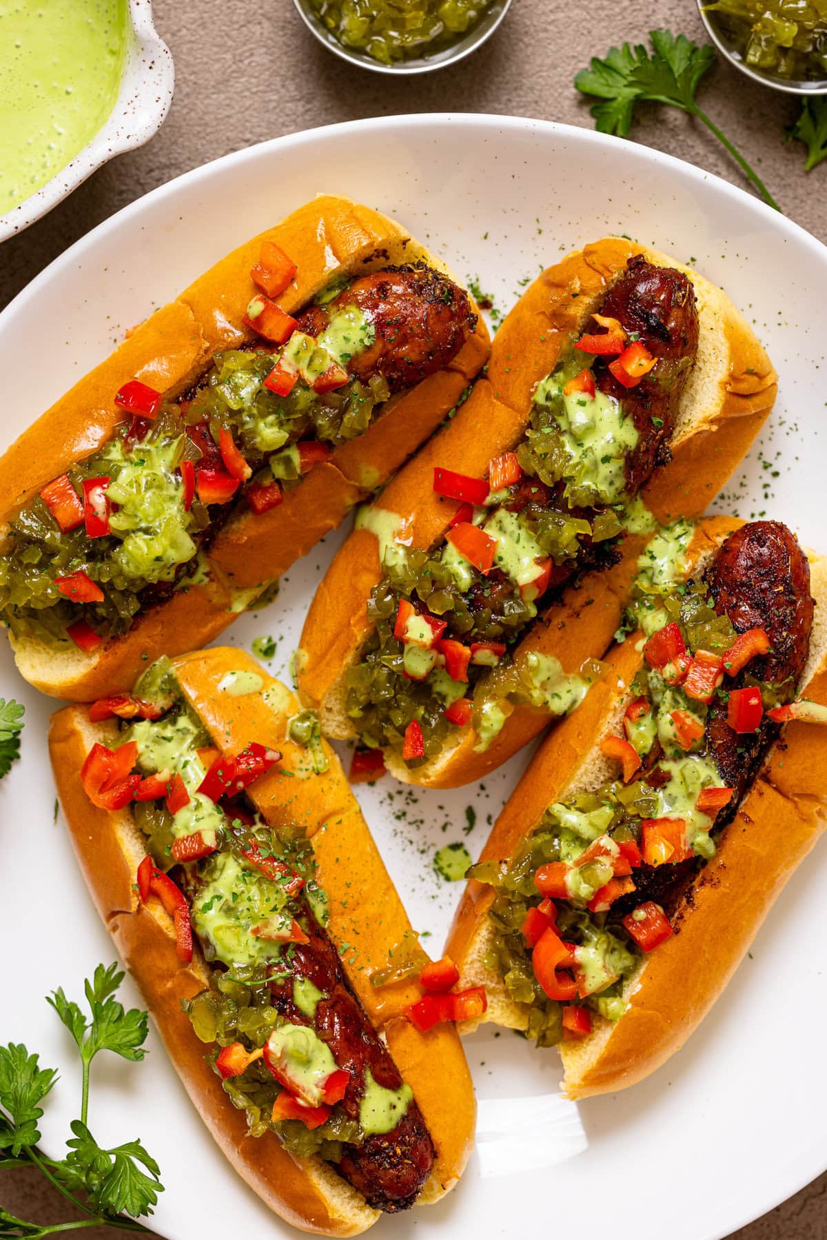 Hot dogs on a white platter with condiments. 