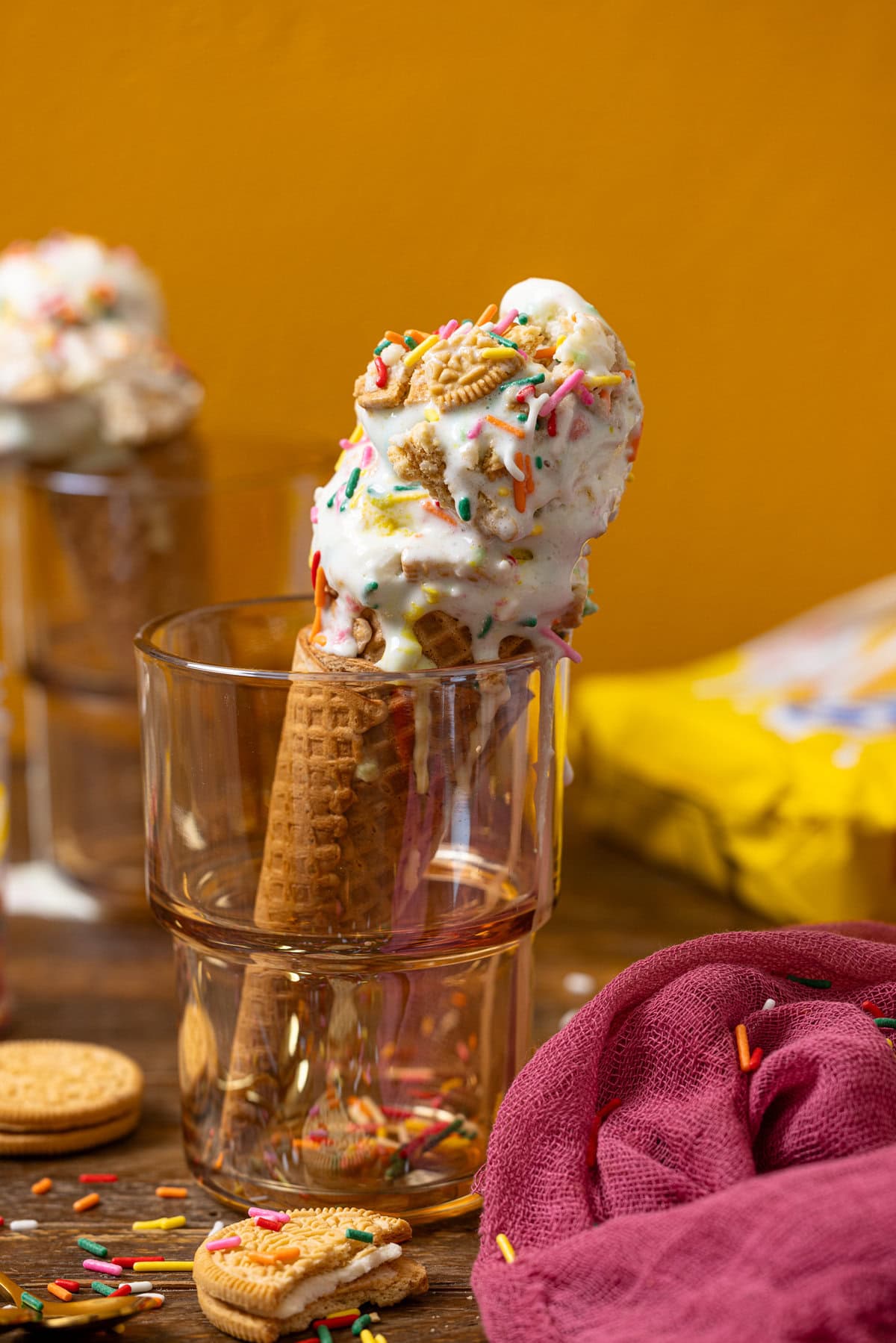 Two ice cream on cones in a glass with Oreo cookies.