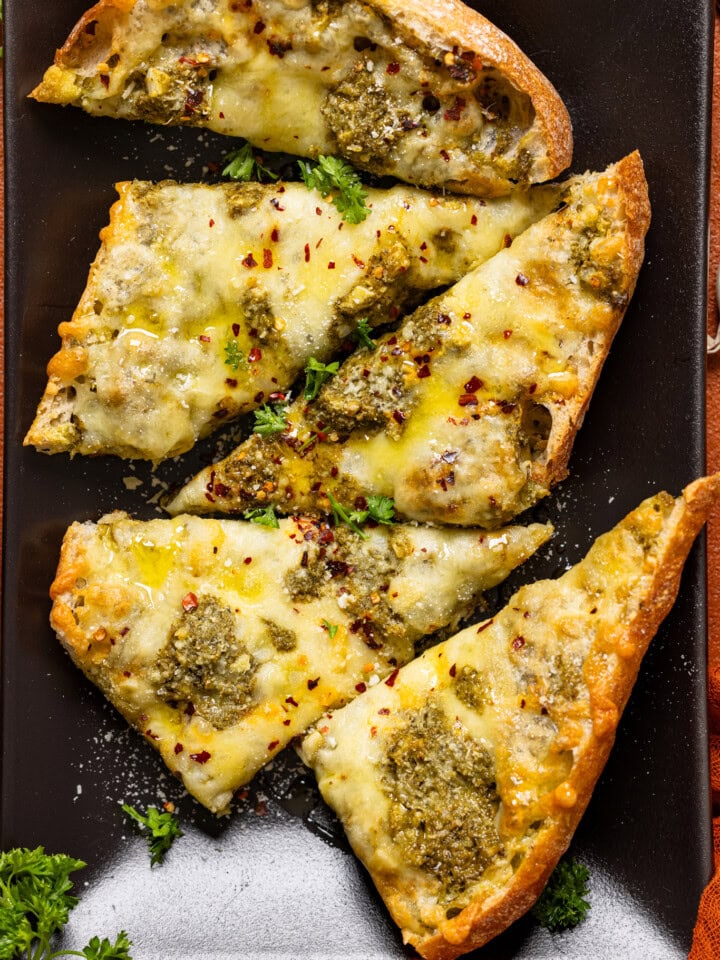 Up close shot of garlic bread on a black platter.