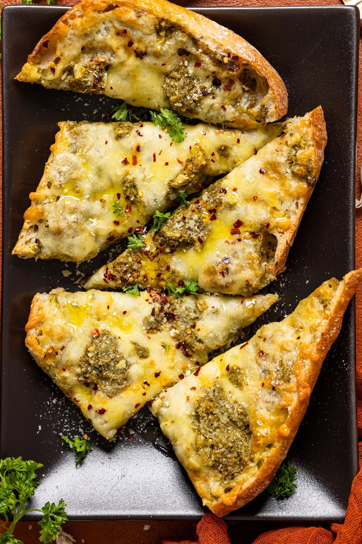 Up close shot of garlic bread on a black platter.
