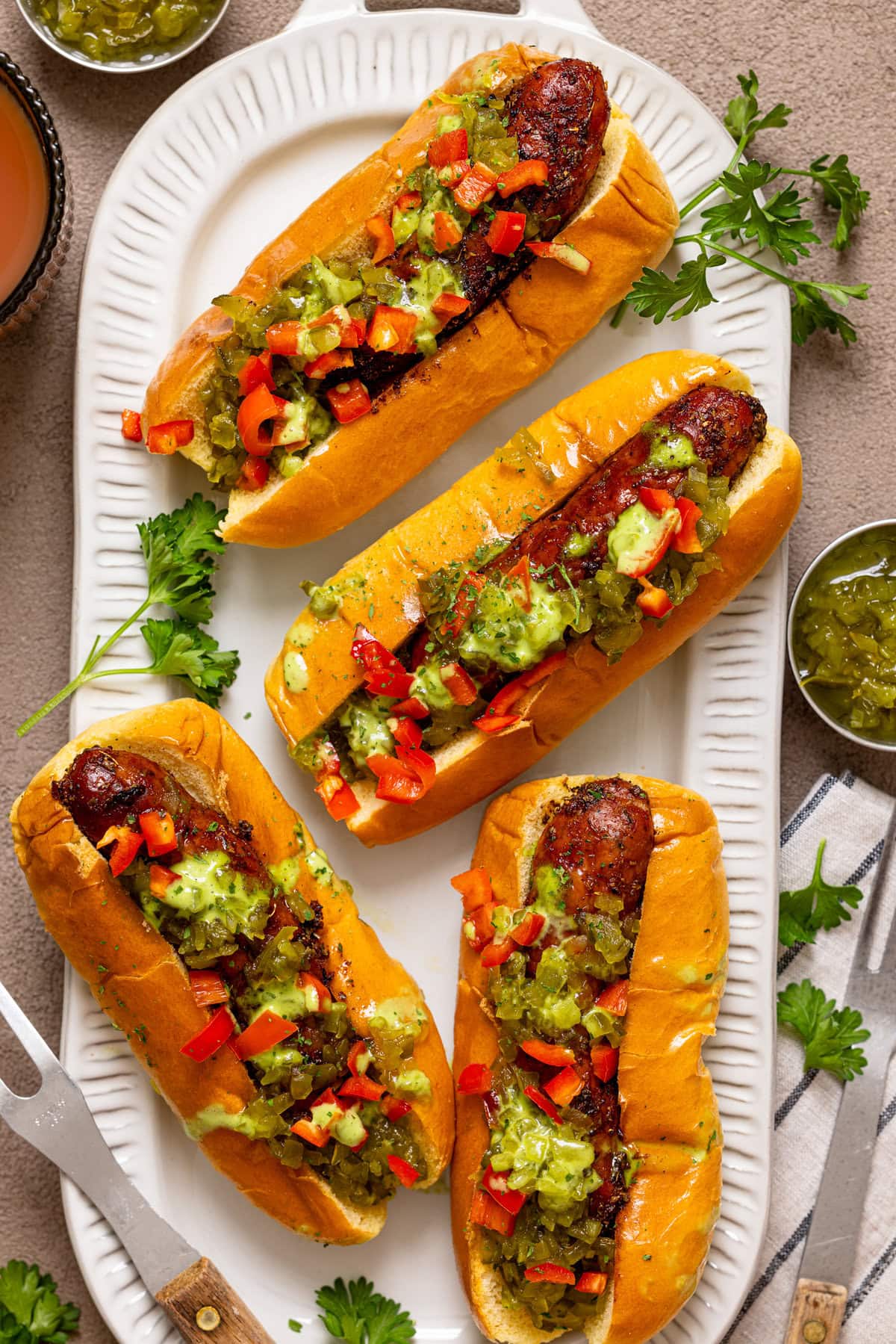 Hot dogs on a platter with condiments and garnish.