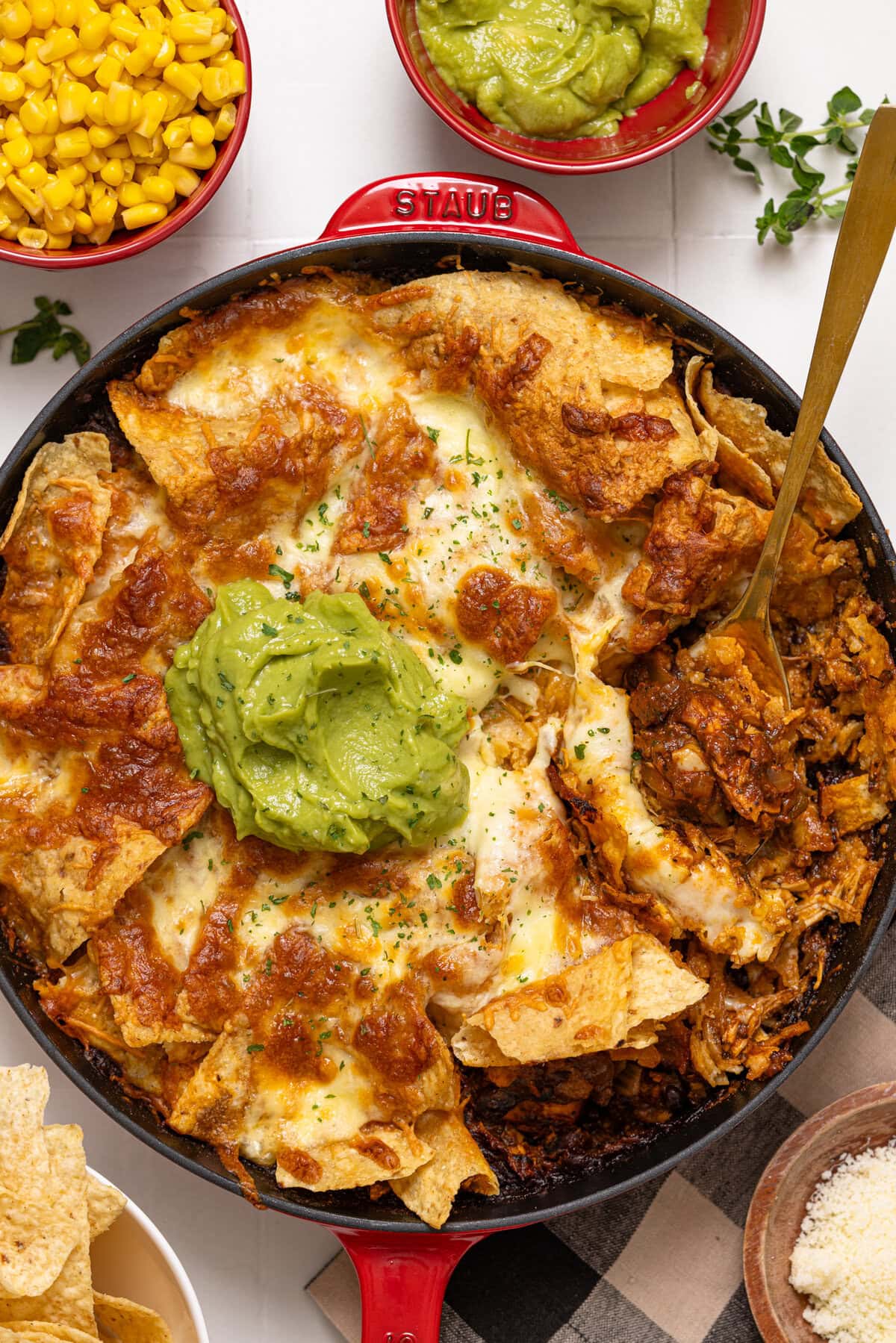 Skillet enchilada with a spoon and toppings.