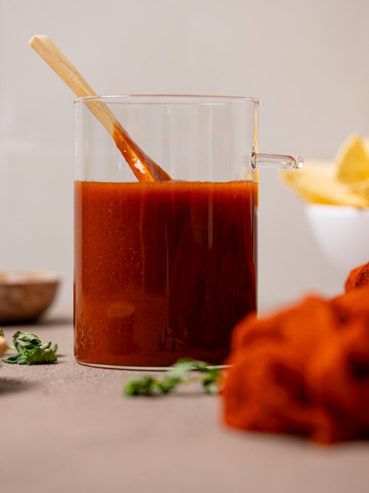 Enchilada sauce in a jar with a wooden spoon.