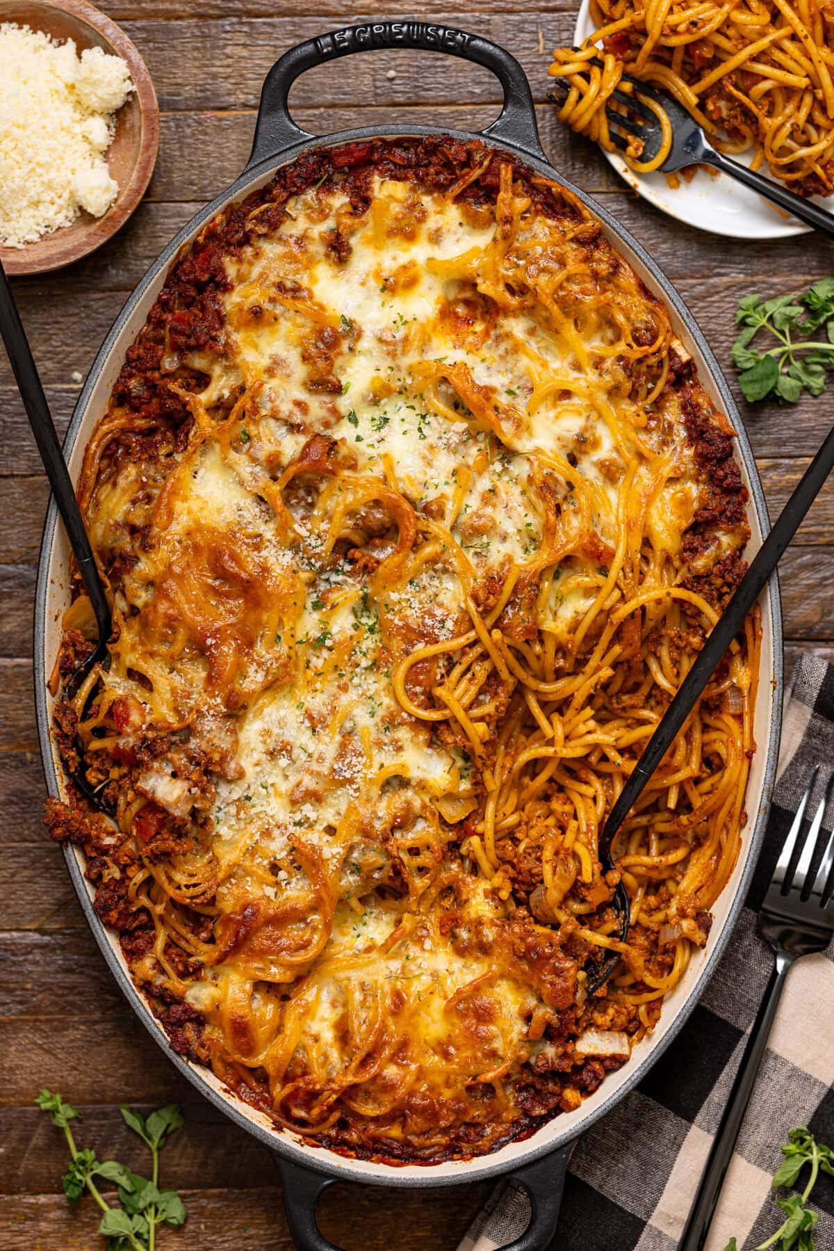 Baked spaghetti dinner with two forks, bread, and forks.