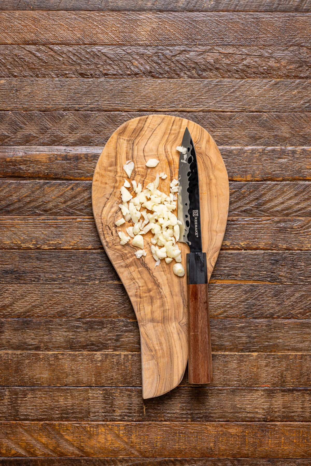 Minced garlic on a cutting board with a knife.
