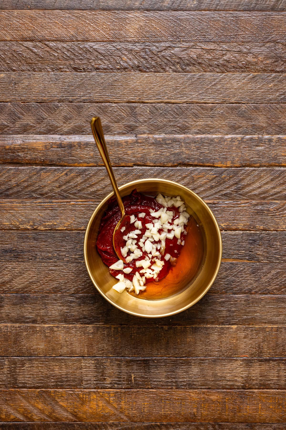 Sauce ingredients in a gold bowl with a spoon.