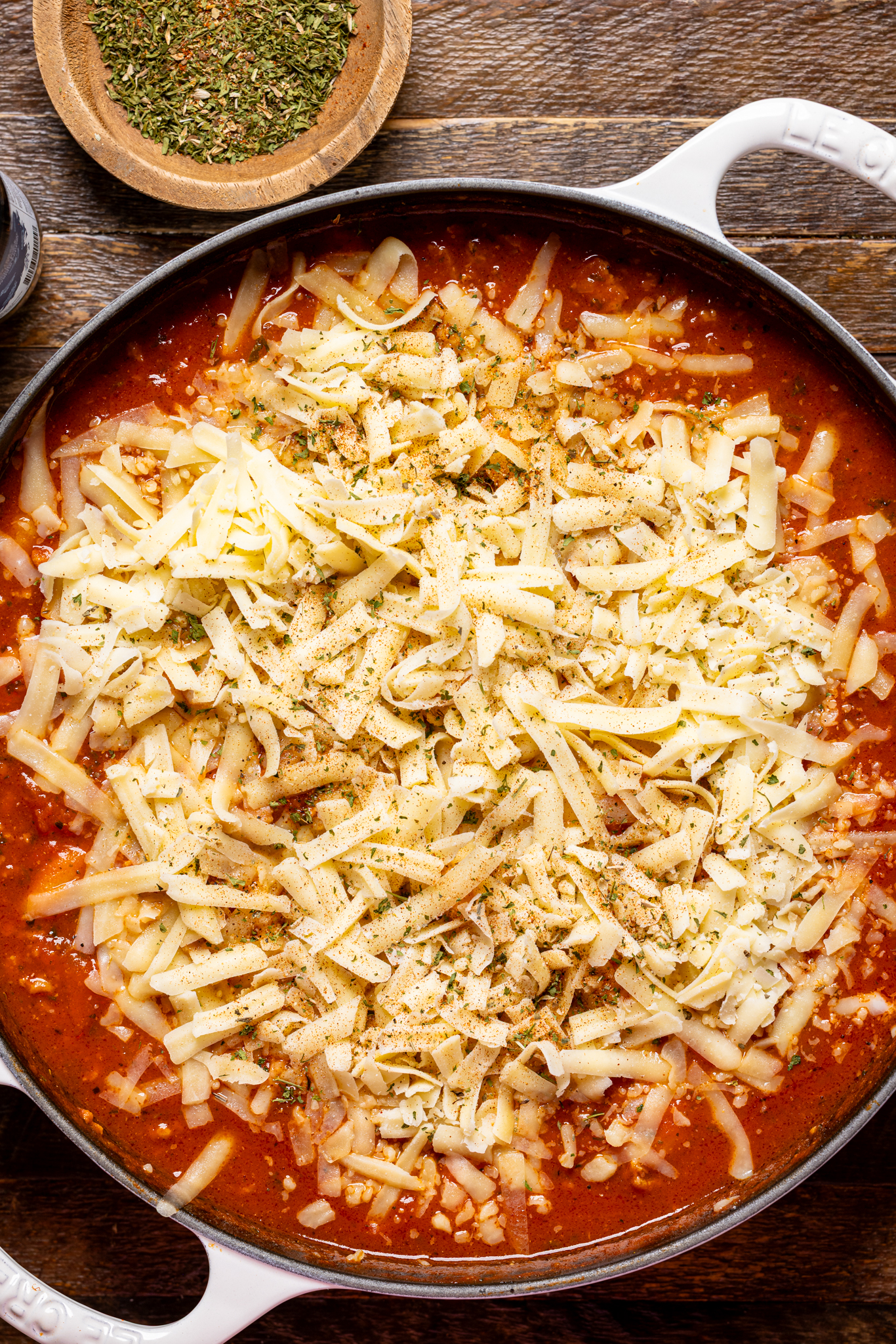 An image of bolognese gnocchi covered with shredded cheese. 