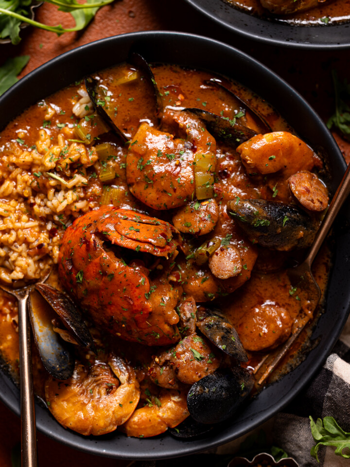 Up close shot of seafood gumbo in black bowls with a spoon.