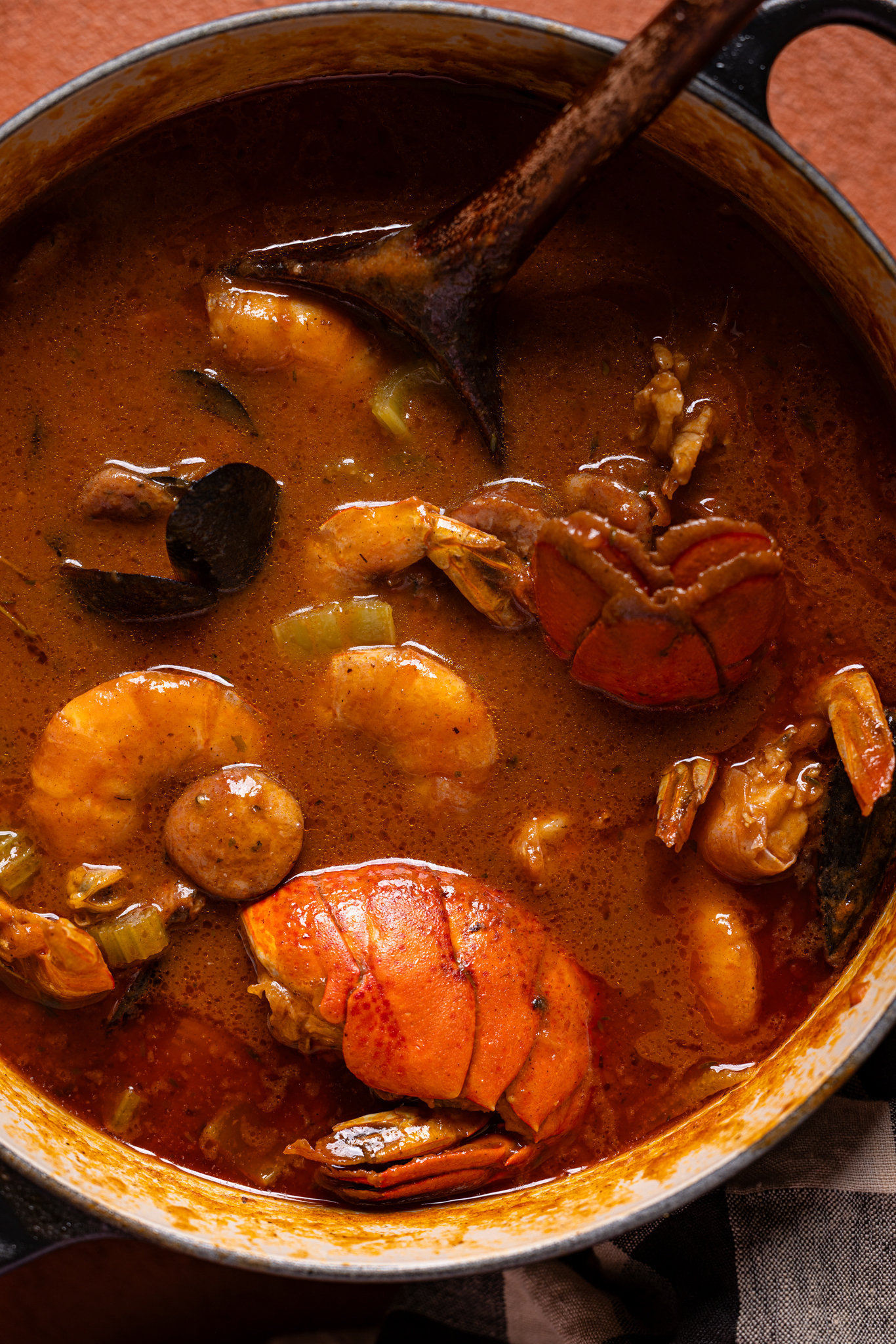 Image of pot with cooked seafood gumbo with a wooden spoon.