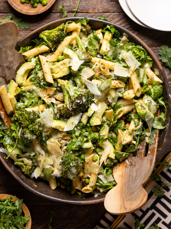 An image of salad in a bowl with serving forks and plates.