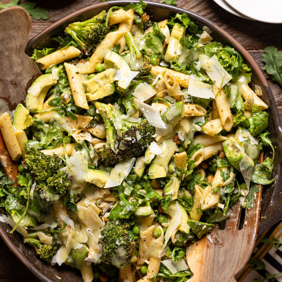 An image of salad in a bowl with serving forks and plates.