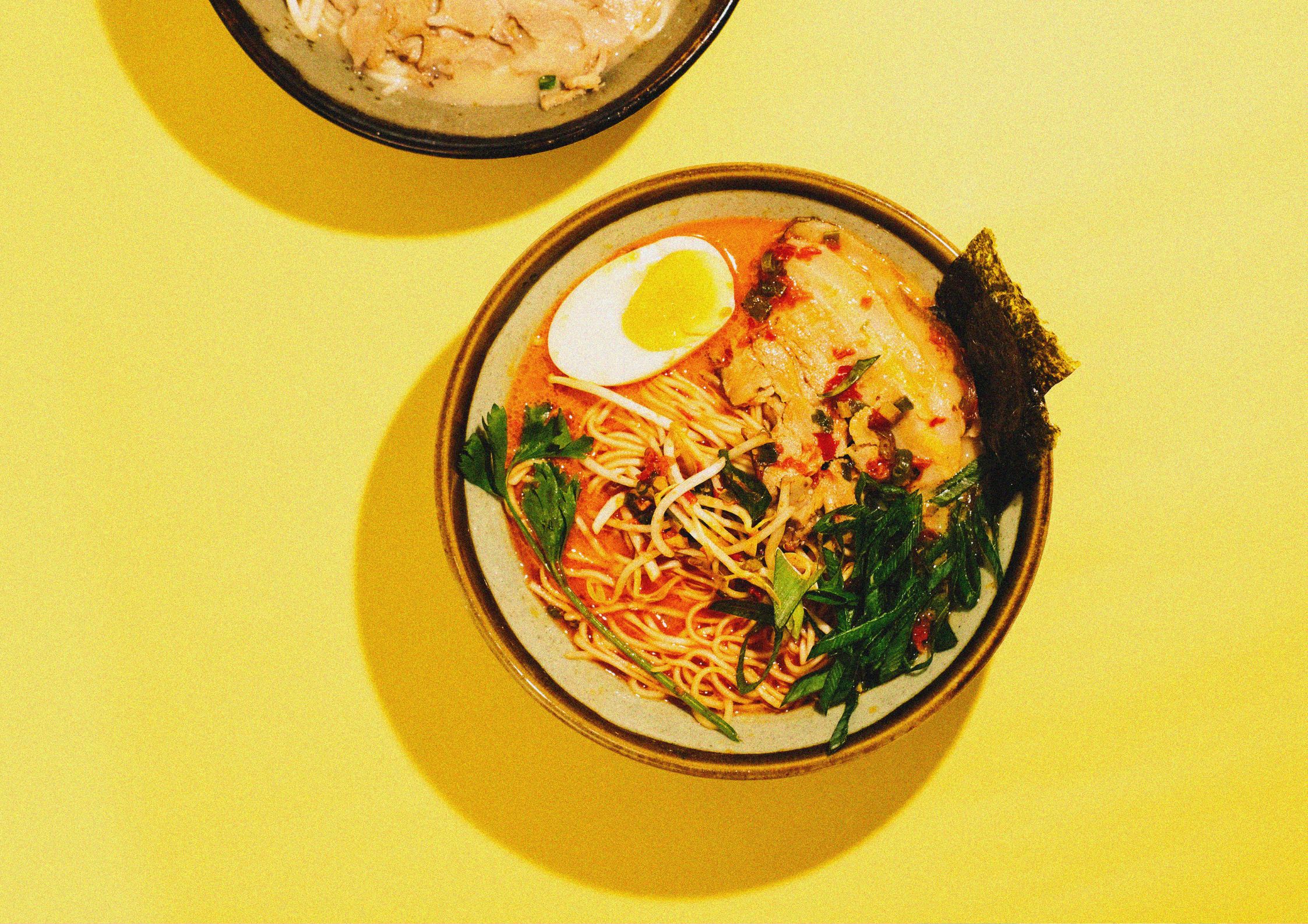 Ramen with toppings overhead with yellow background