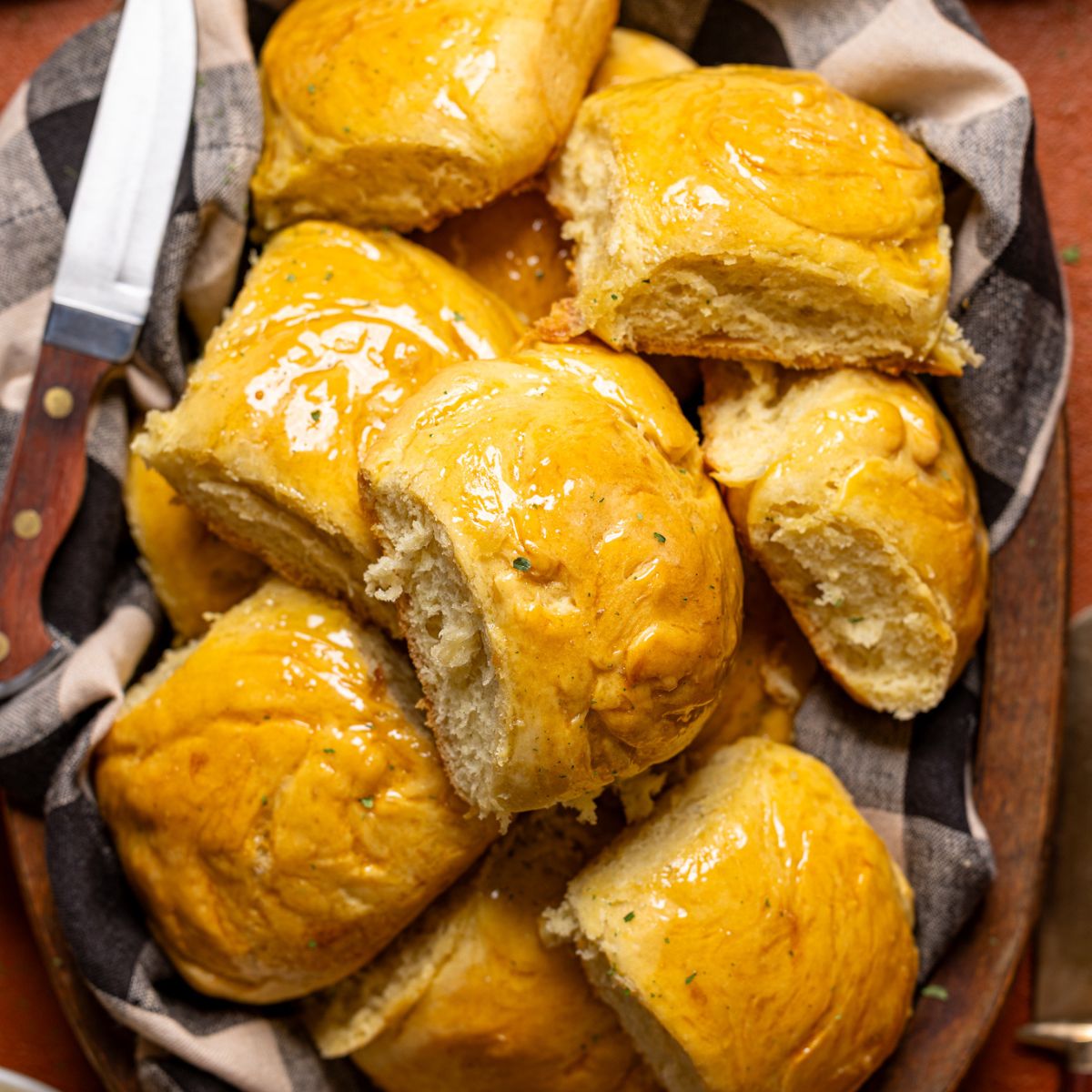 Up close shot of baked dinner rolls in a basket with black/white cloth.