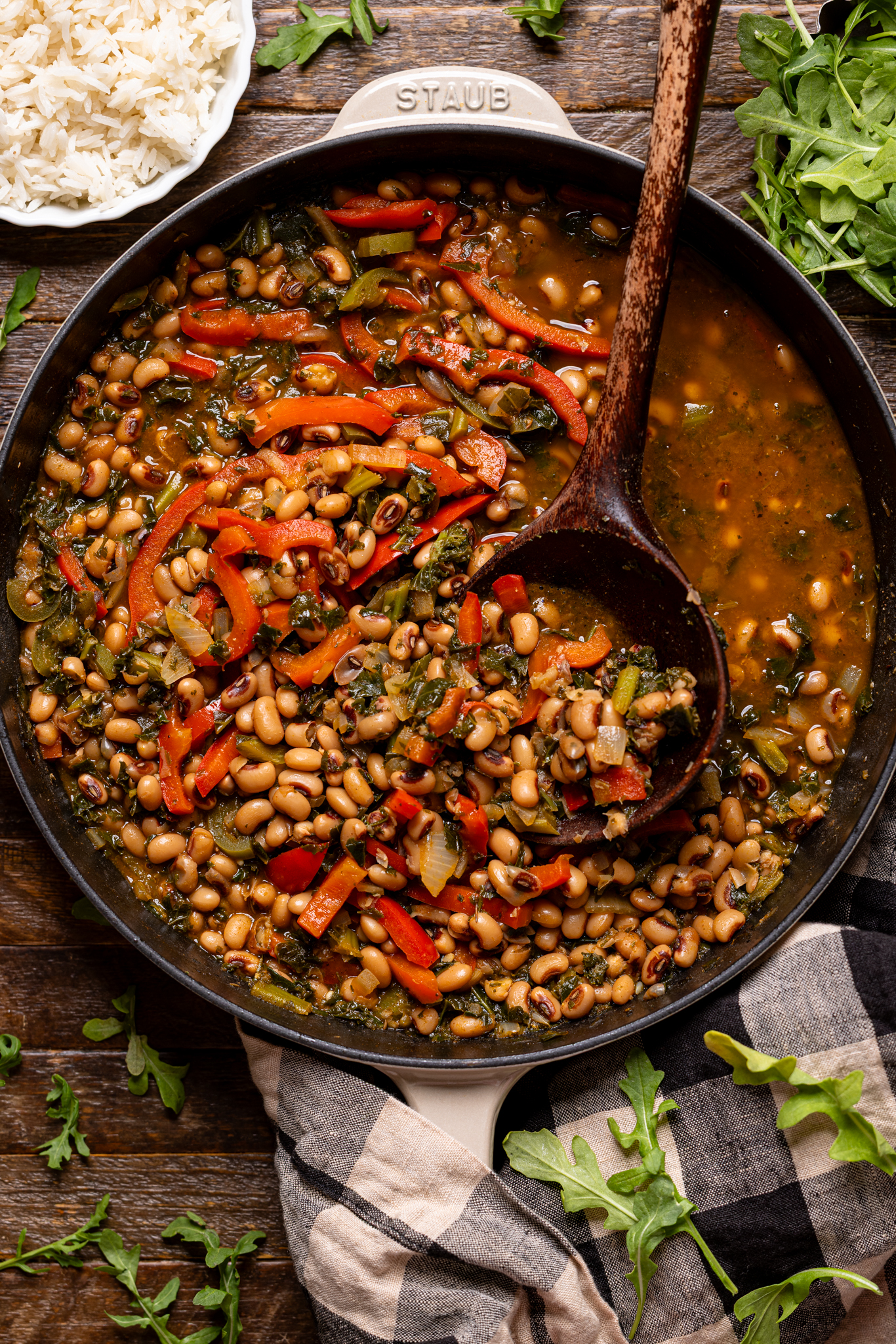 Image of cooked black eyed peas in a skillet with a wooden spoon.