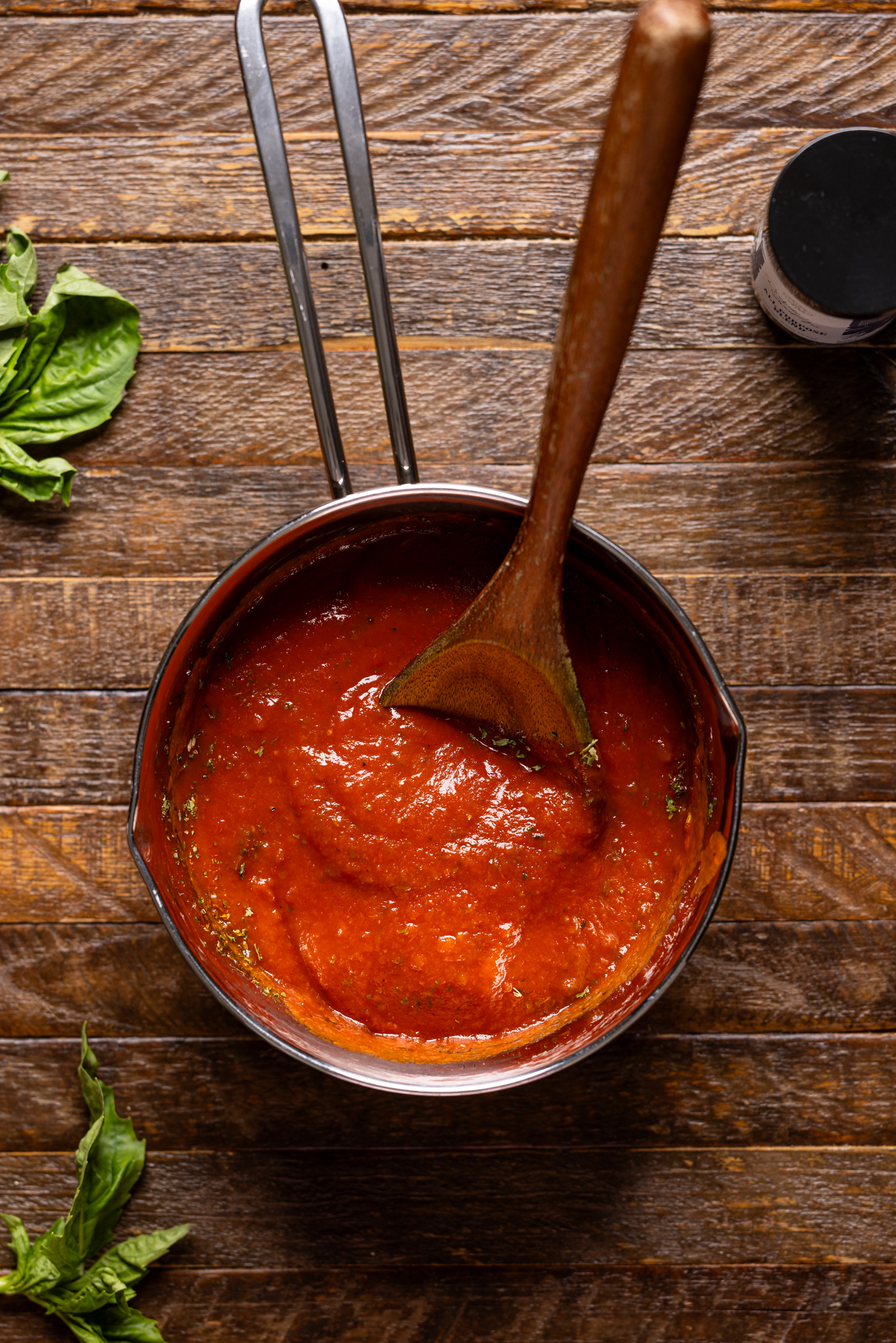 Image of pizza sauce in a pot on a brown wood table.