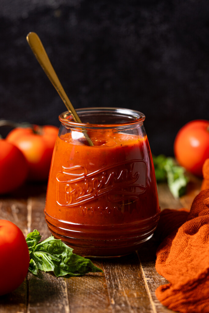 Image of pizza sauce in a jar with a spoon.