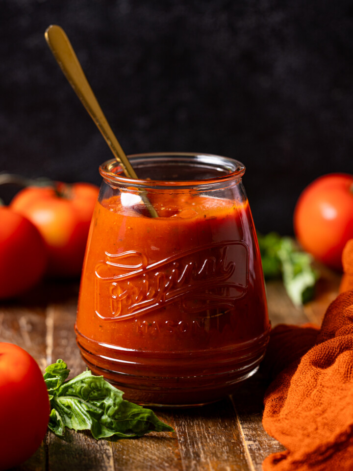Image of pizza sauce in a jar with a spoon.