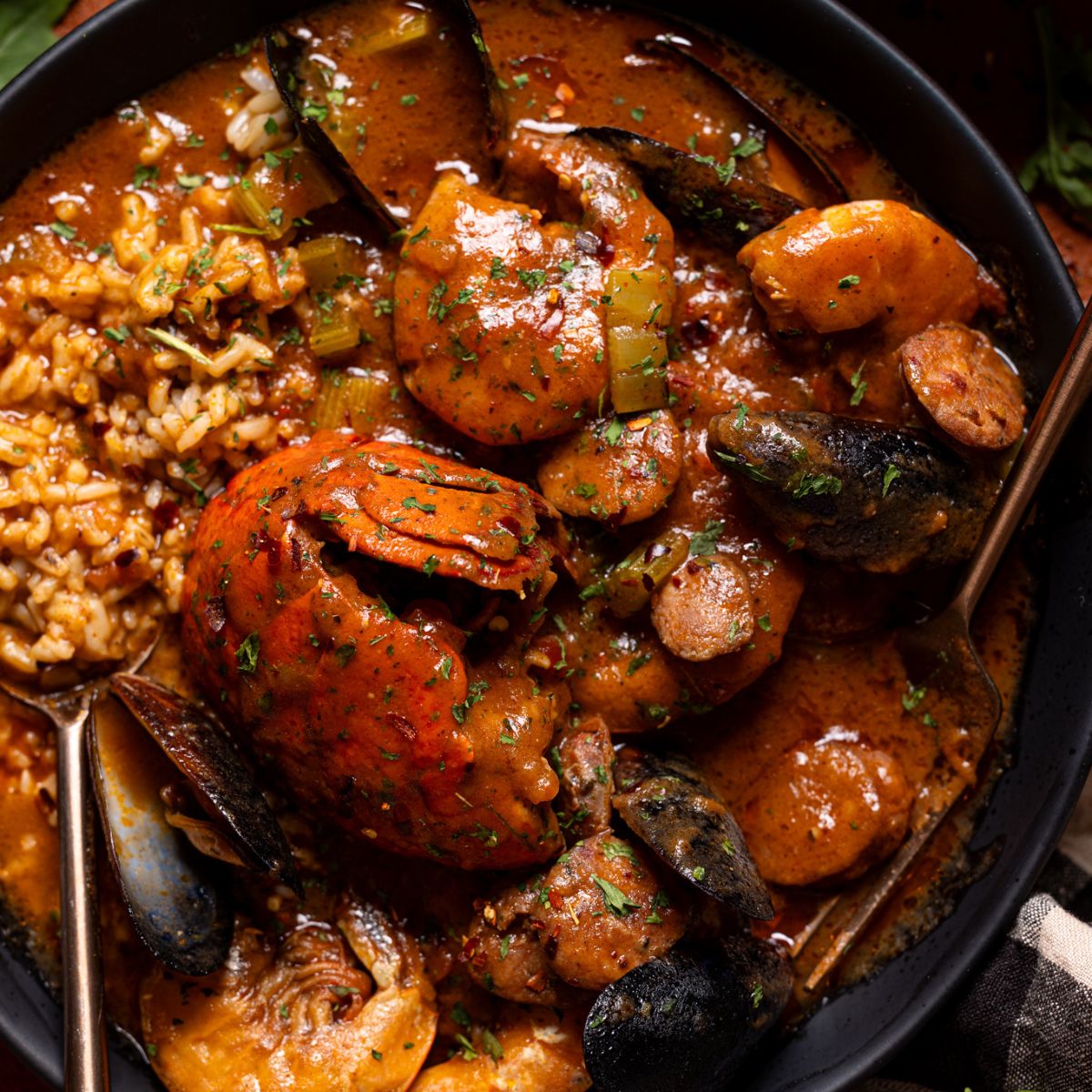 Up close shot of seafood gumbo in black bowls with a spoon.