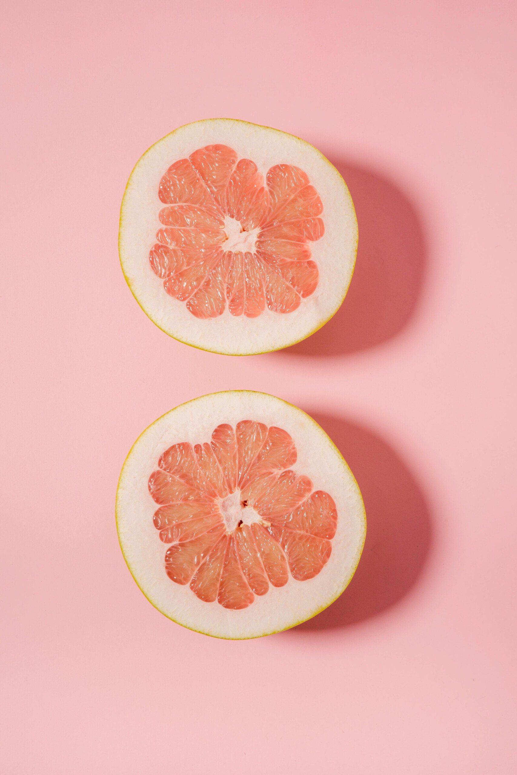 Grapefruit cut in half on pink background