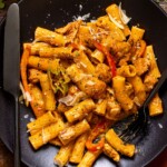 Up close shot of the Jerk Chicken Rasta Pasta on a plate with utensils.