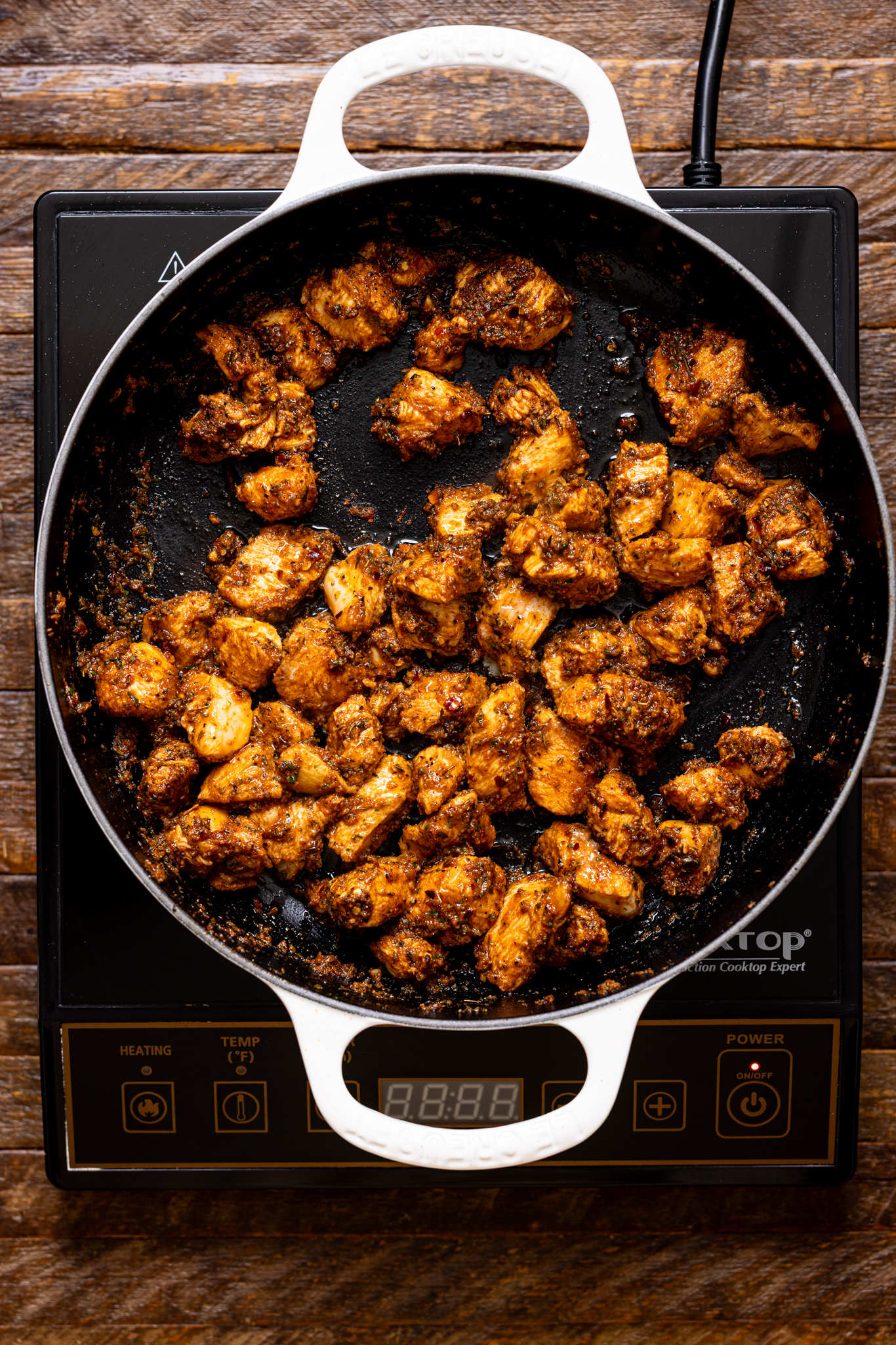 Image of sautéed jerk chicken in a pot over the stovetop.