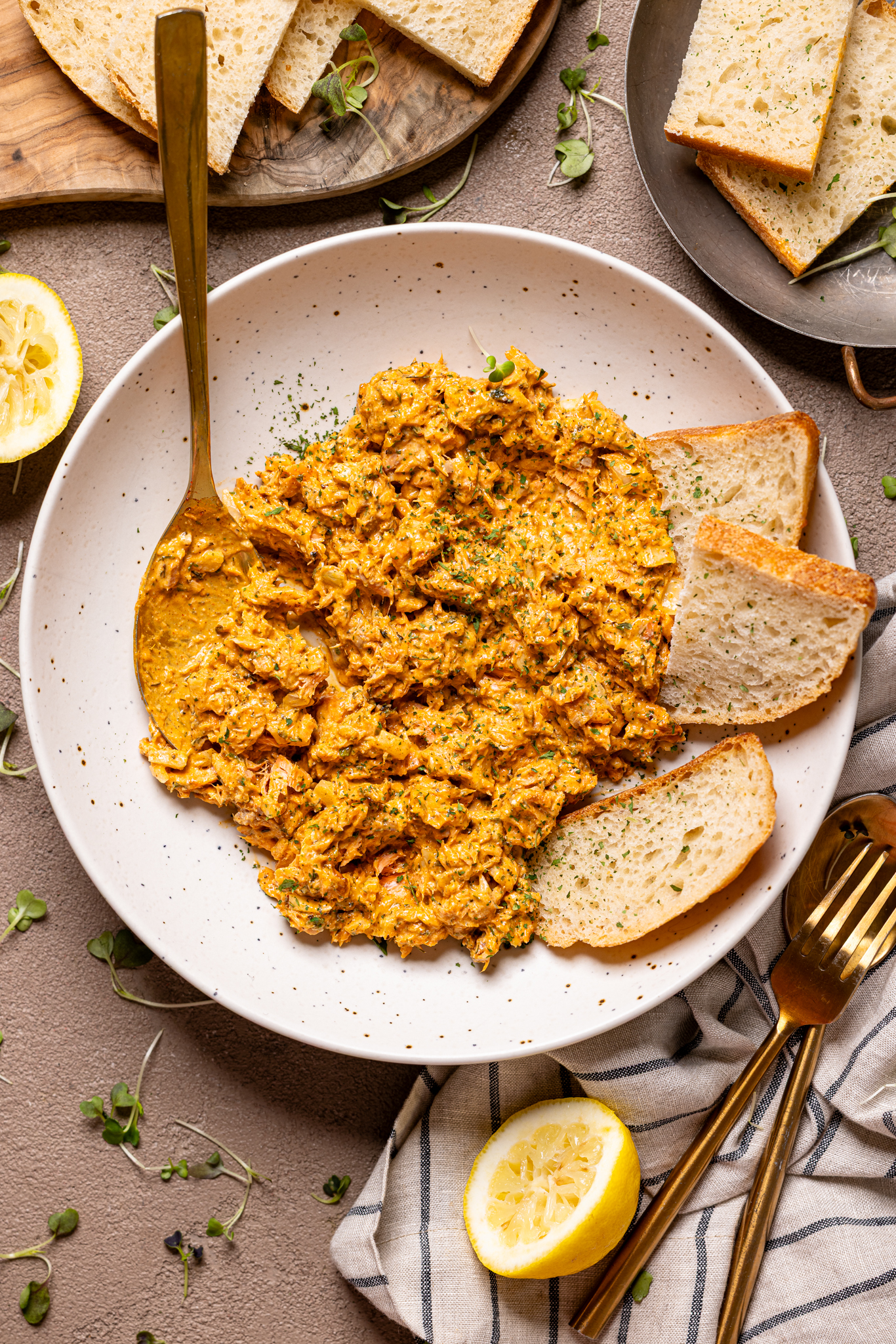 Image of salmon dip on a plate with utensils and sliced bread.