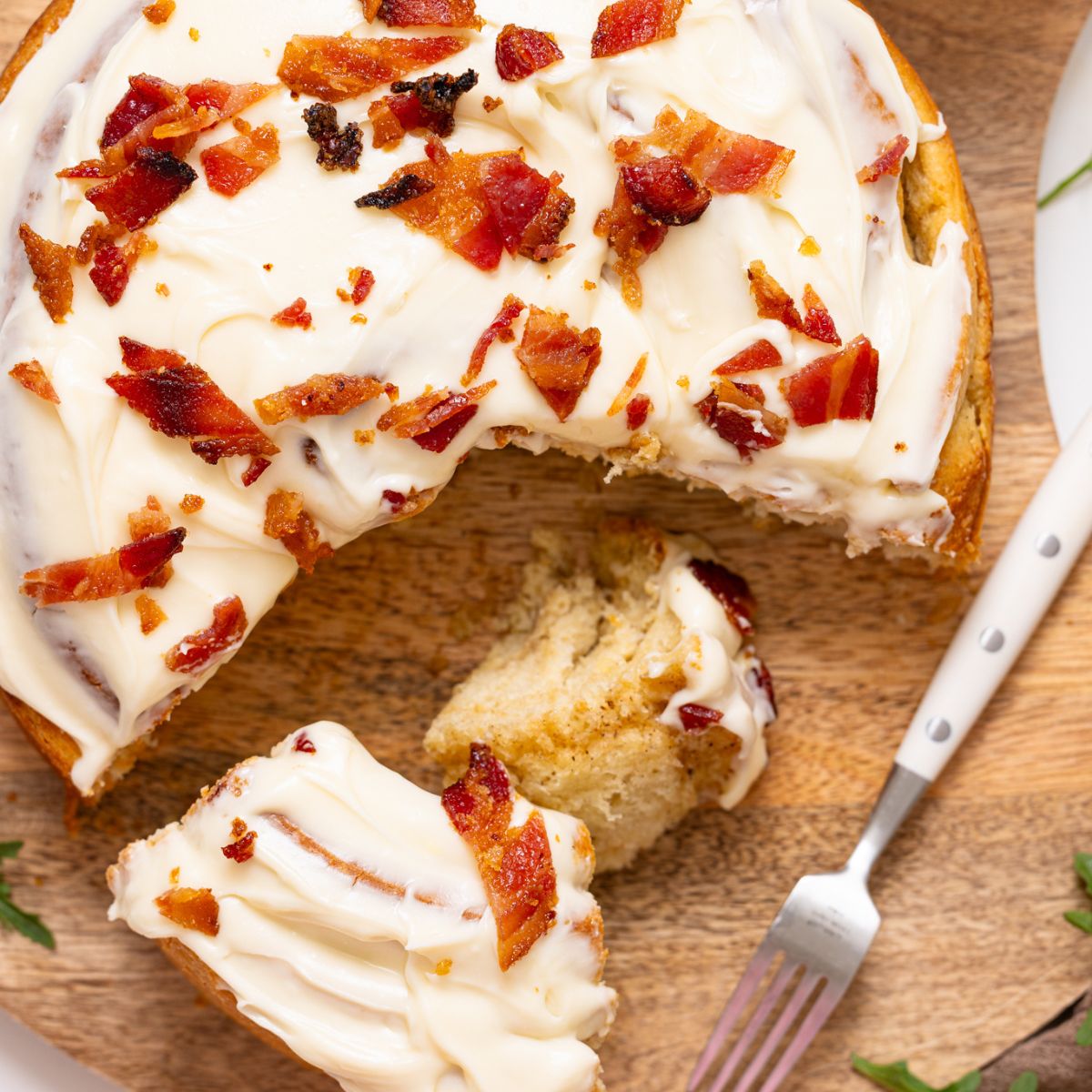 Overview shot of giant cinnamon roll on a platter sliced and with a fork.