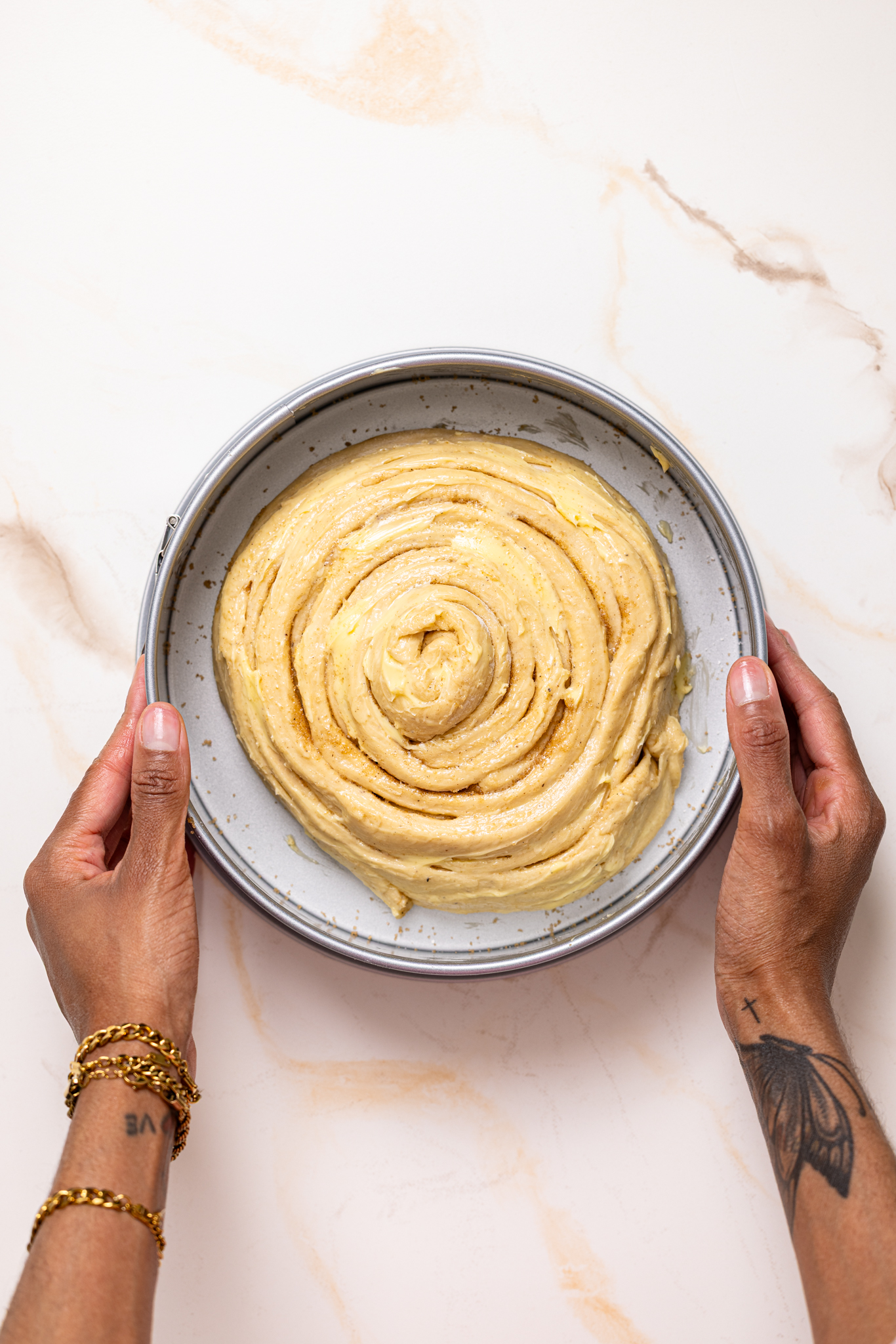 The prepared and shaped dough inside the baking pan being held by woman hands.
